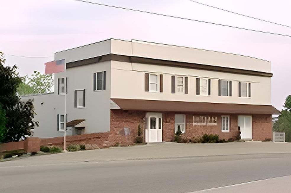 Two-story building with a brown awning and an American flag. Beige and brick exterior, windows.