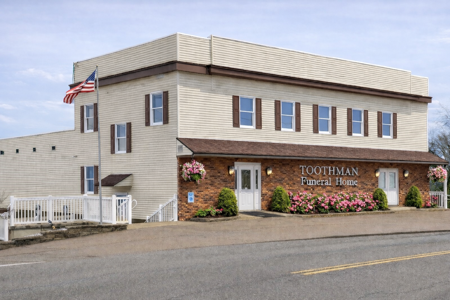 Two-story building with a brown awning and an American flag. Beige and brick exterior, windows.