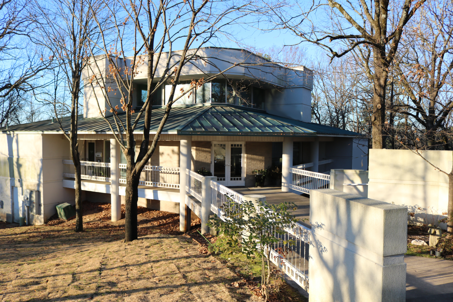 A white house with a green roof and a white fence