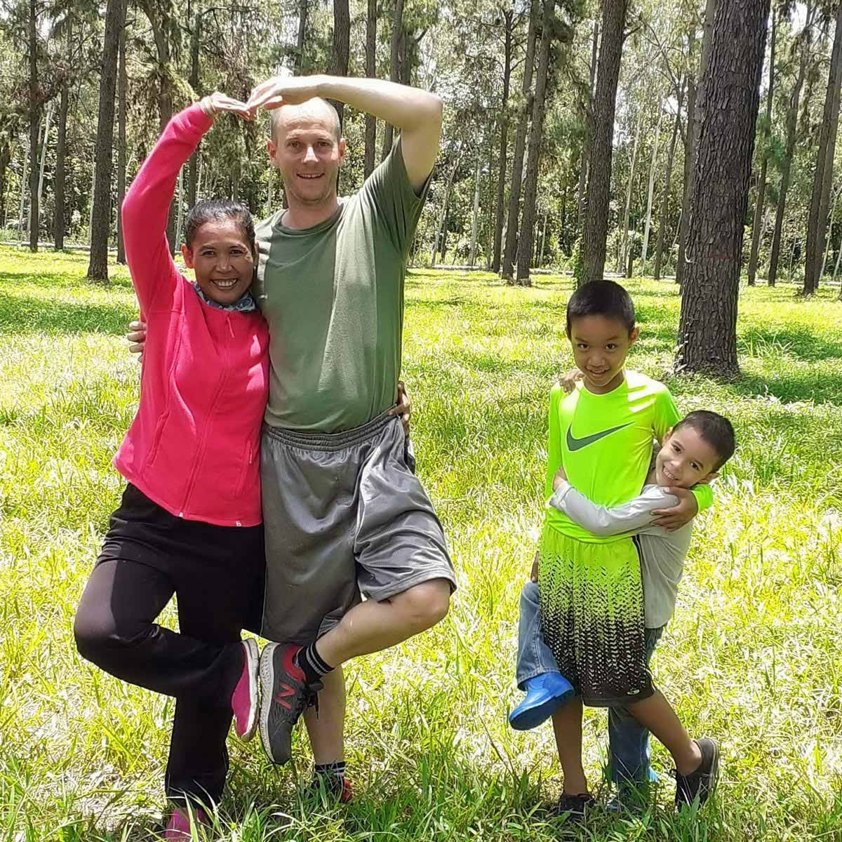 A family is posing for a picture in the woods.