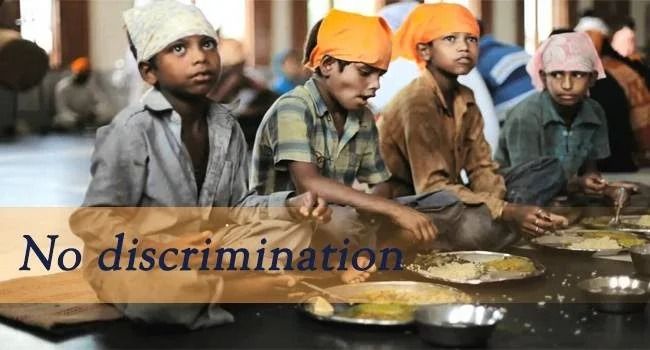 A group of children are sitting at a table with plates of food.