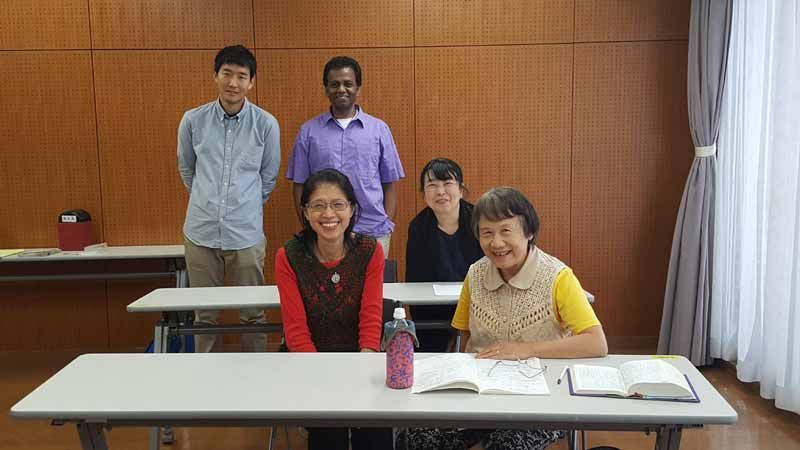 A group of people are sitting at a table in a classroom.