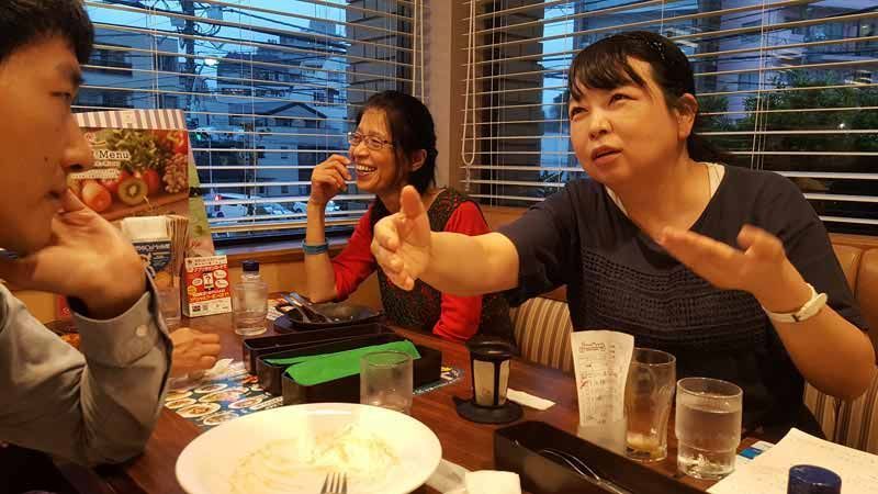 A group of people are sitting at a table in a restaurant talking to each other.