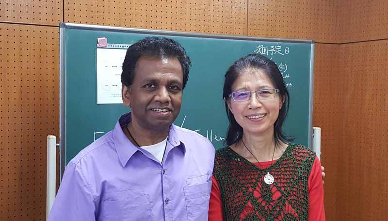 A man and a woman are posing for a picture in front of a blackboard.