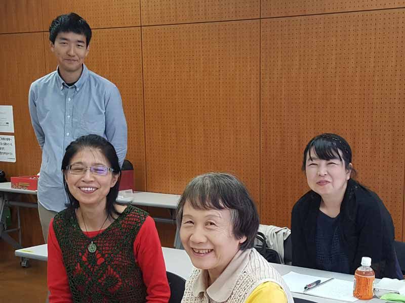 A group of people are posing for a picture while sitting at a table.