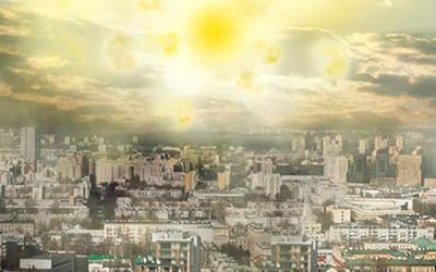 An aerial view of a city with the sun shining through the clouds.