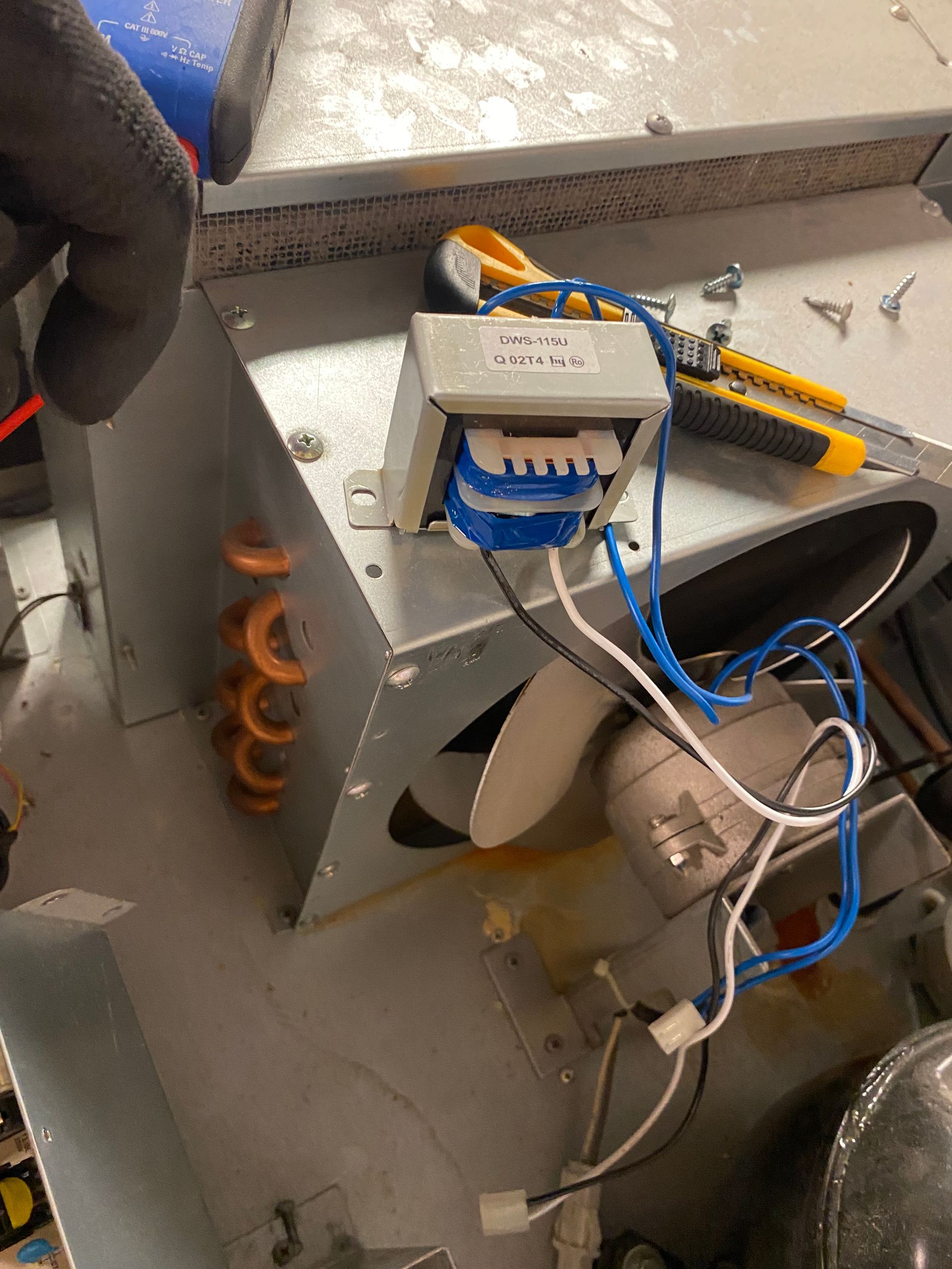 A close-up of electrical components inside a metal box. Wires and transformer are visible.