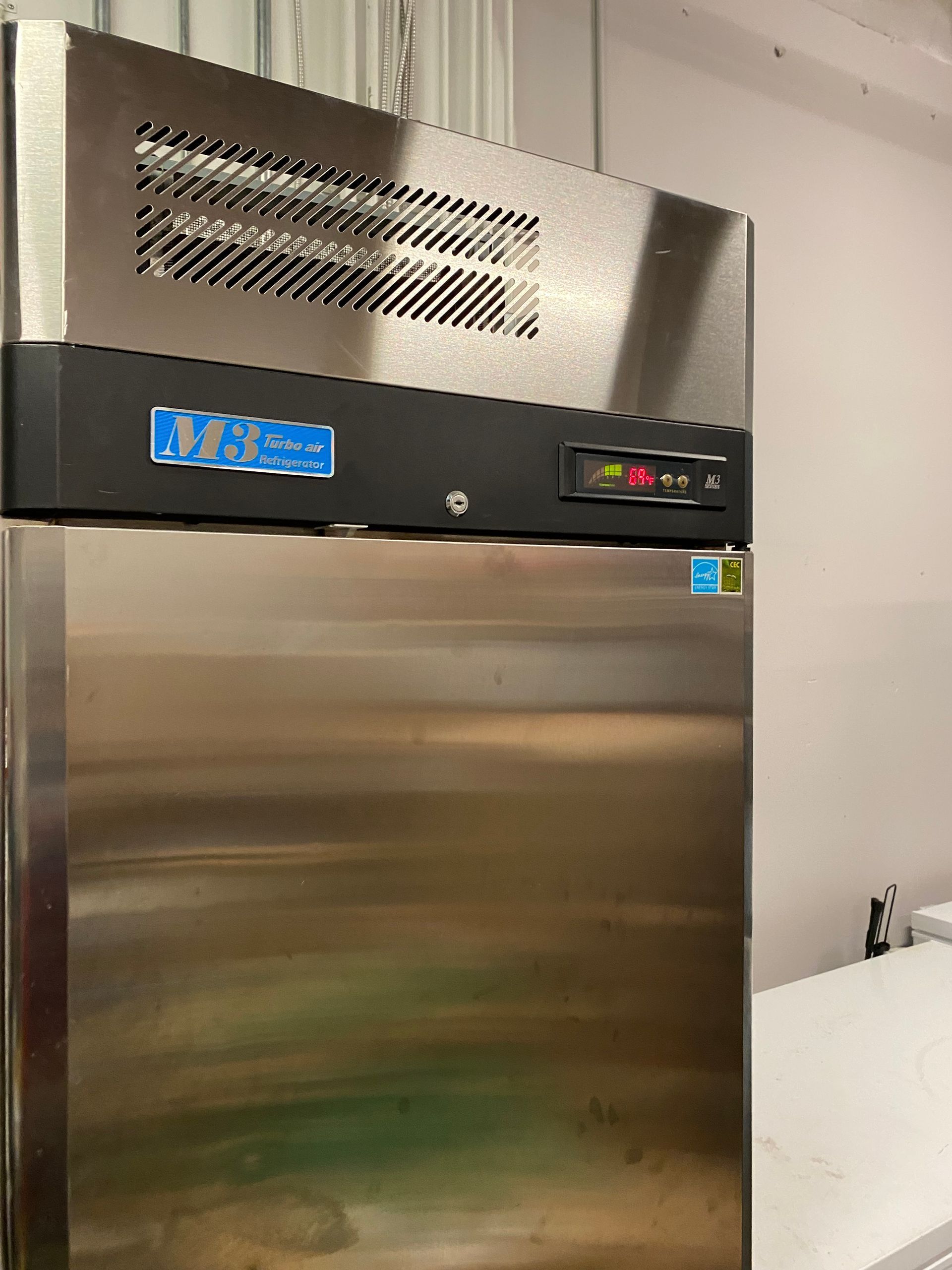 Stainless steel commercial refrigerator with digital temperature display.