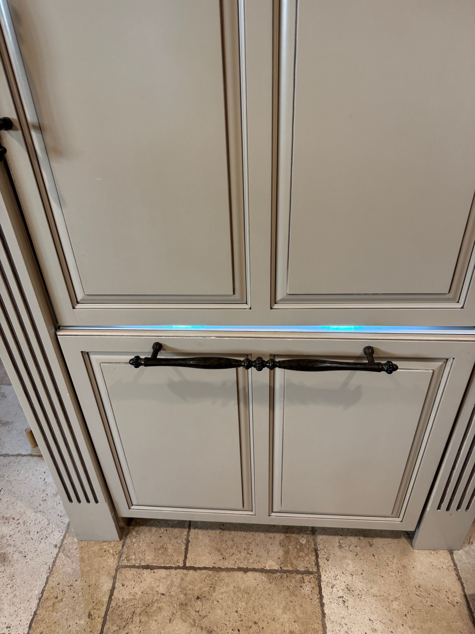 Beige kitchen cabinet doors with black handles and an overhead light.