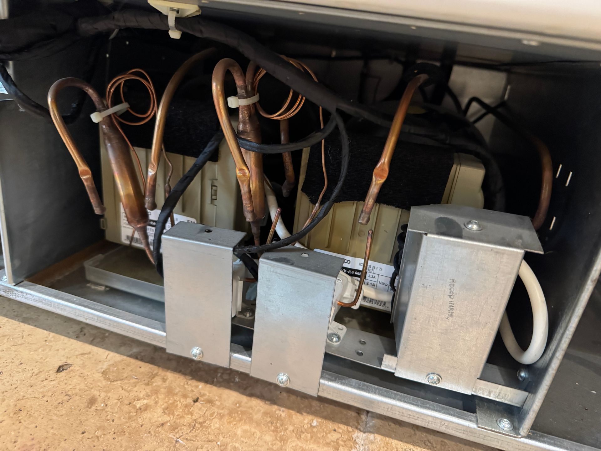 Close-up of a refrigerator's interior with copper tubing and metallic components.