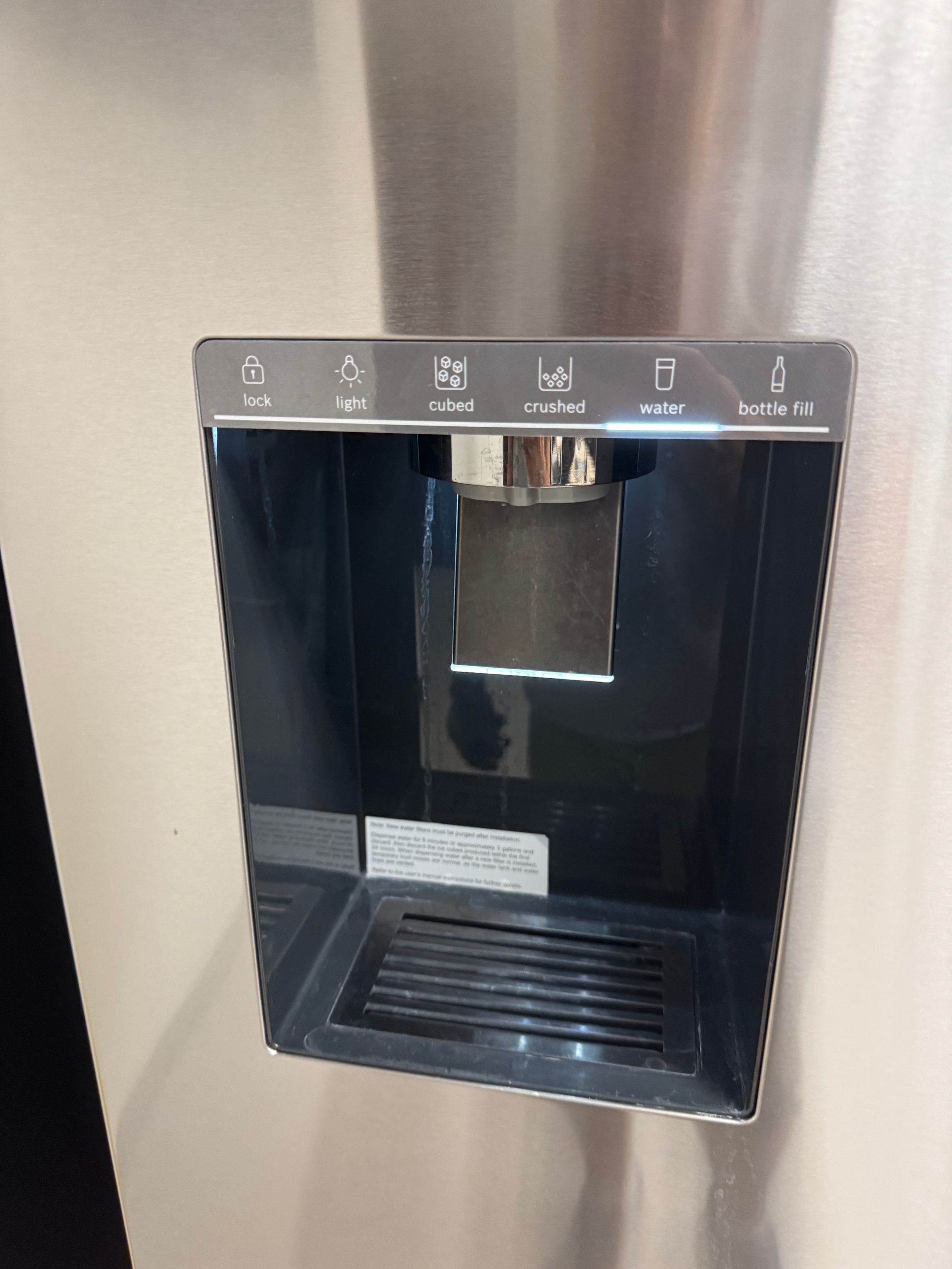 Stainless steel refrigerator water/ice dispenser with control panel.