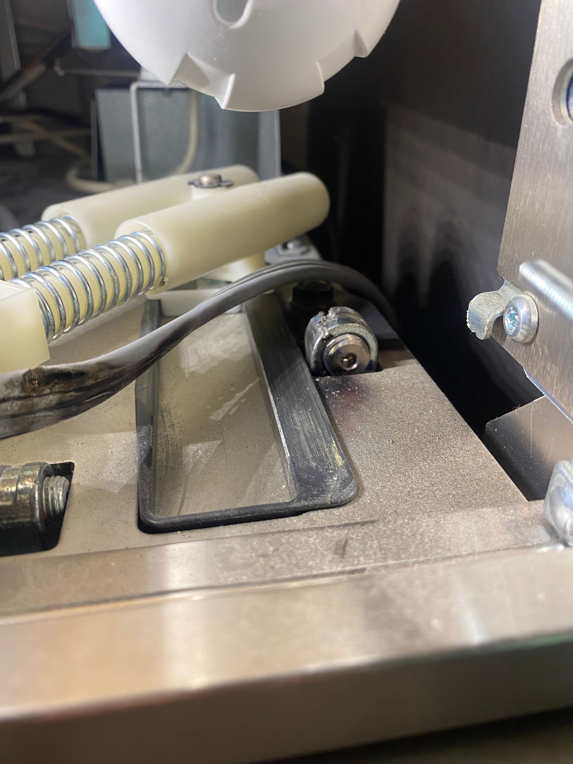 Close-up of a machine's interior with metal components, a bolt, and a white, rounded object.