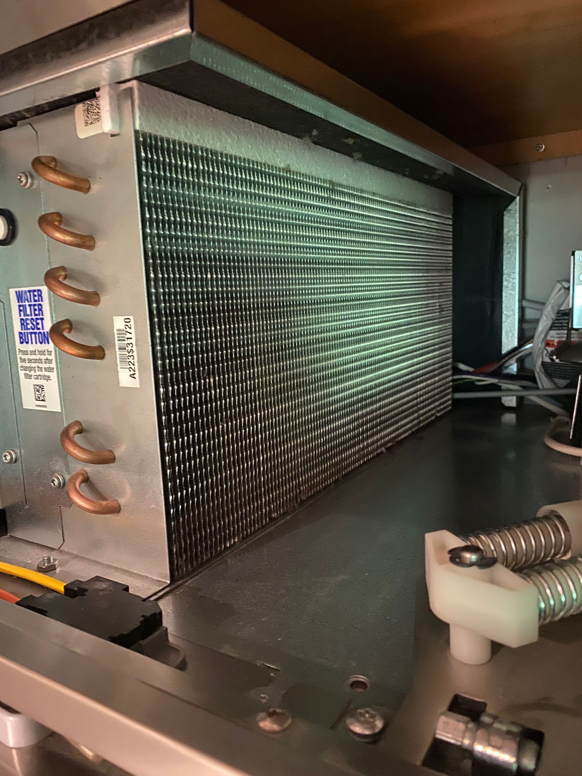 Inside view of a refrigeration system's evaporator coil with copper tubing and metal fins.