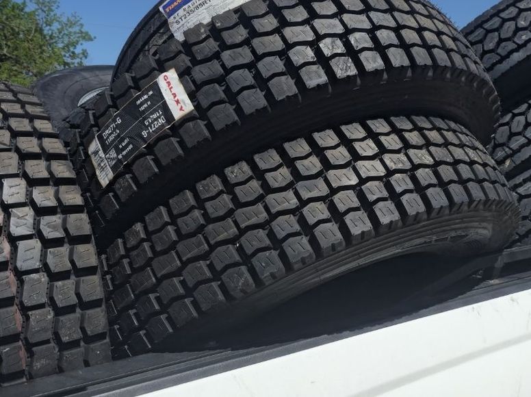 A bunch of tires are stacked on top of each other on the back of a truck.