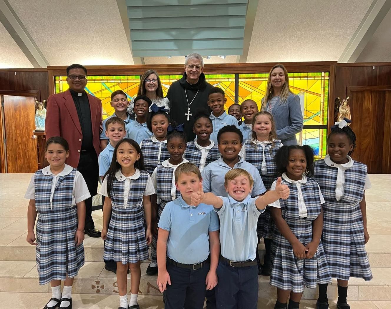 A group of children posing for a picture in front of a stained glass window