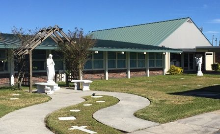 A statue of jesus is in front of a building with a green roof