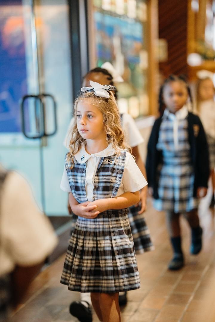 A group of young girls in school uniforms are walking down a hallway.
