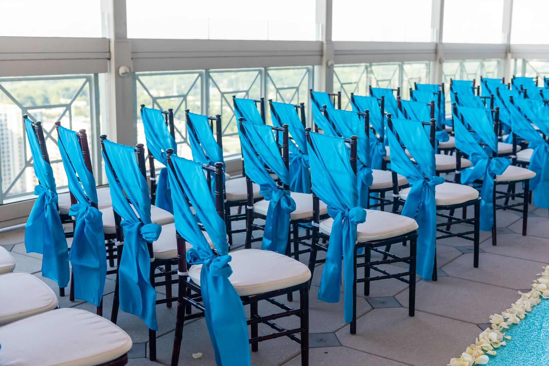 A row of blue chairs are lined up in front of a window.