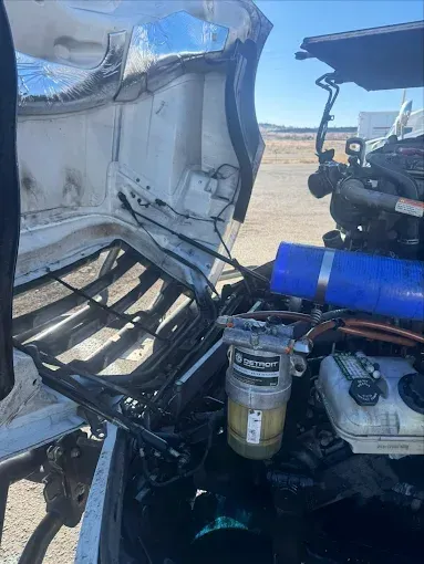 A close up of the engine of a truck with the hood open.
