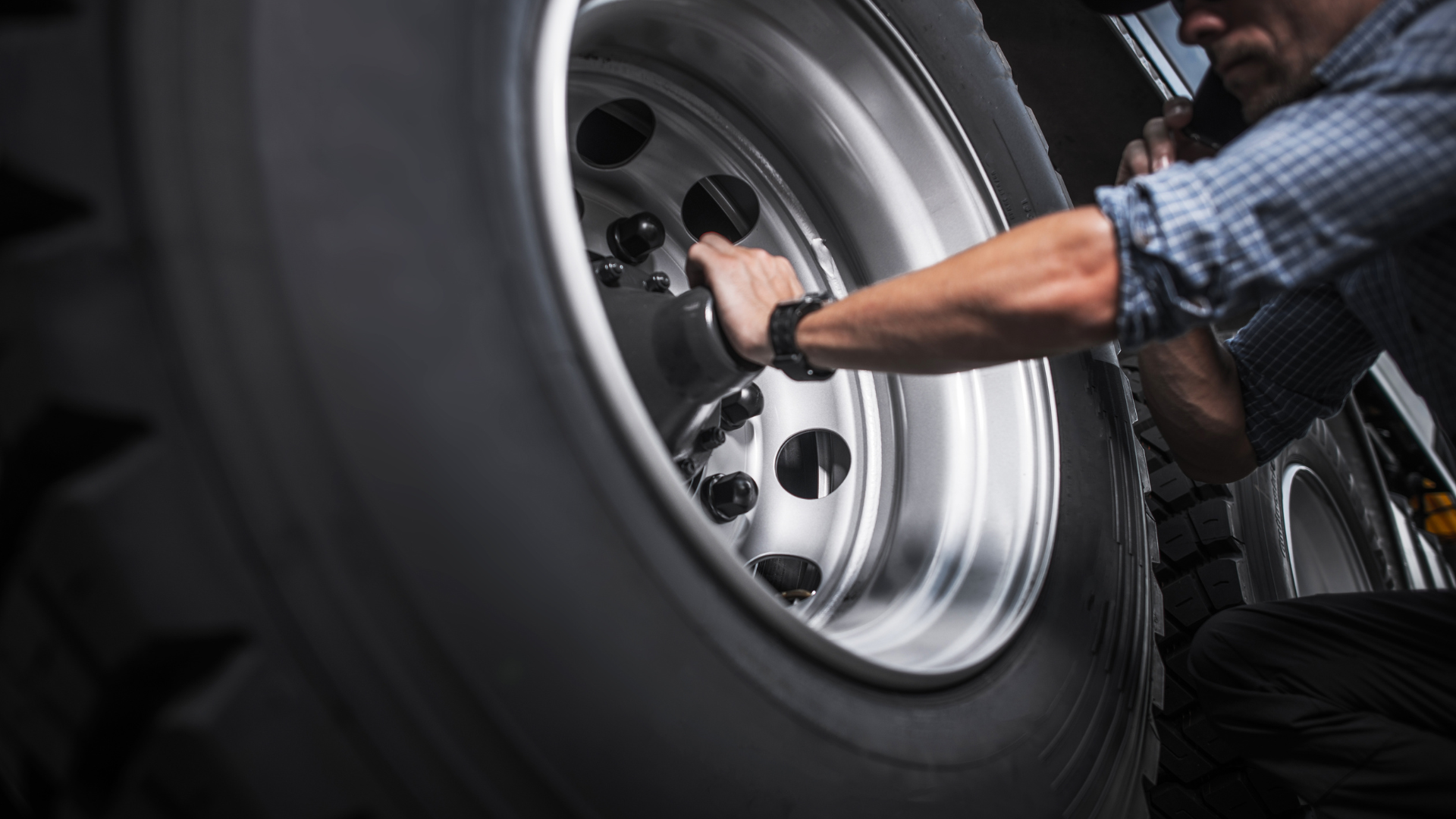 A man is changing a tire on a semi truck.
