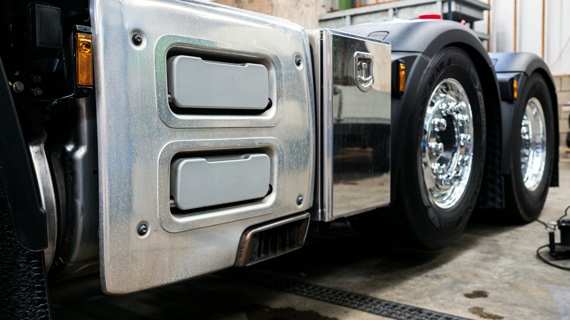 A silver semi truck is parked in a garage.