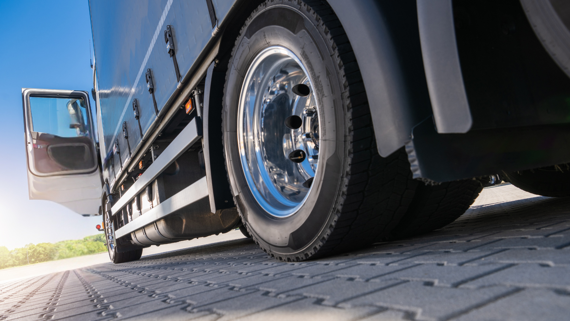 A semi truck is parked on a brick road with its door open.