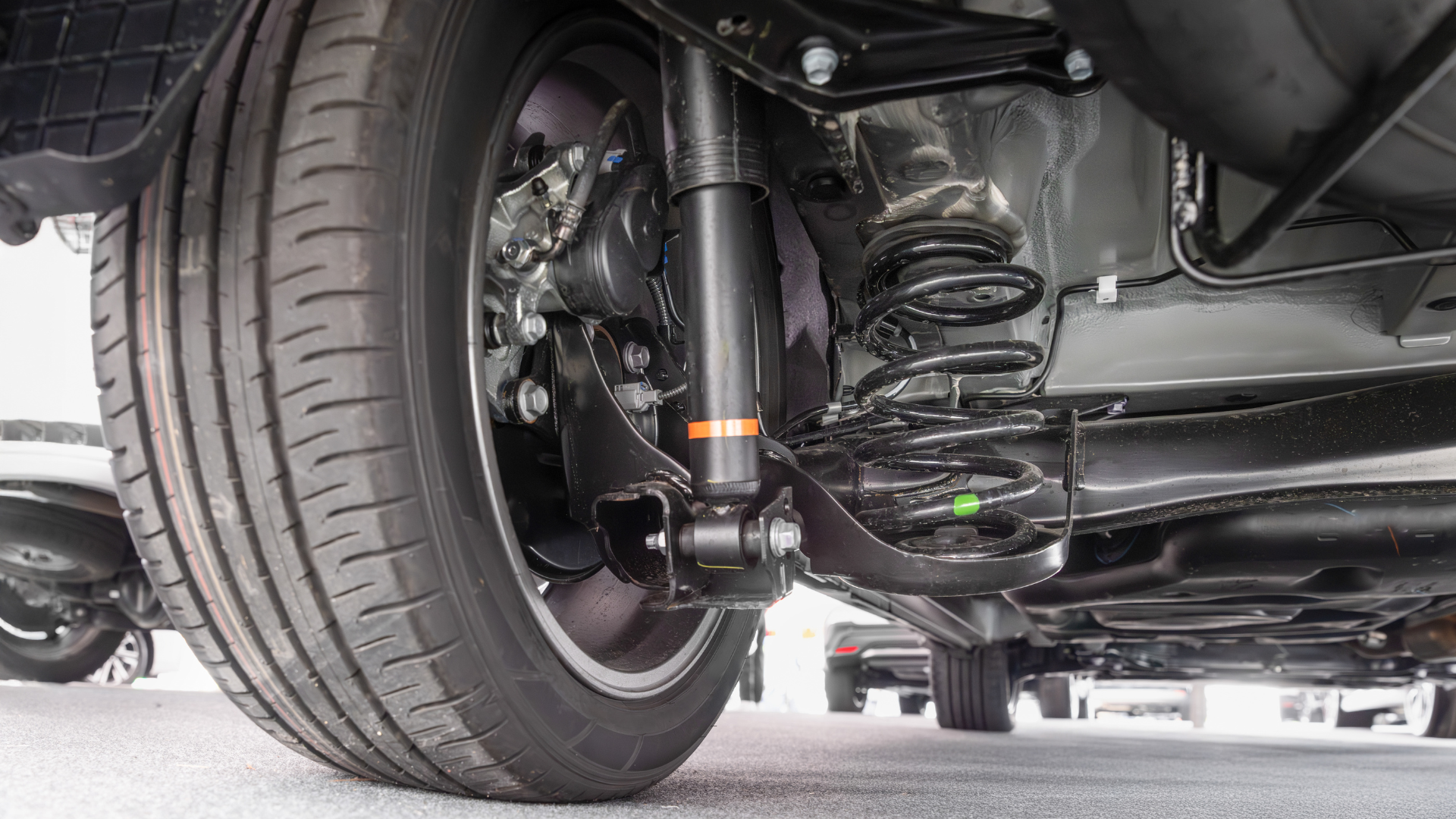 The underside of a car with a shock absorber and a tire.