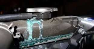 Close-up of a metal pipe joint with turquoise corrosion or leak residue on a dark surface