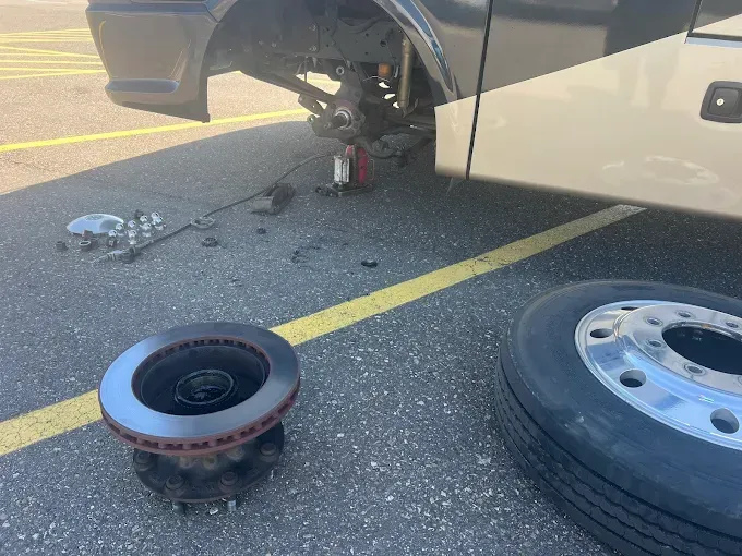 A brake disc is sitting on the ground next to a tire.