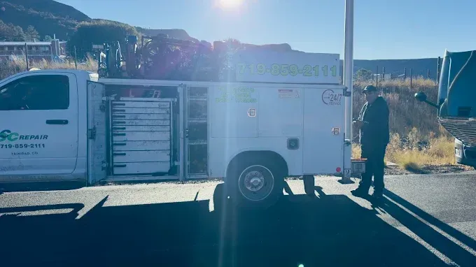 A man is standing next to a white truck on the side of the road.