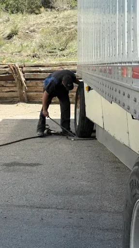 A man is pumping a tire on a semi truck.