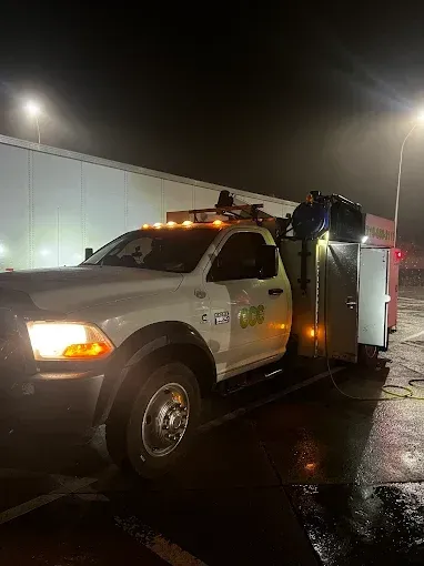 A white truck is parked in a parking lot at night.