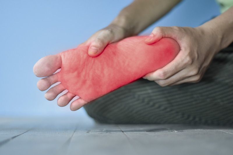 A person is holding their foot in pain.