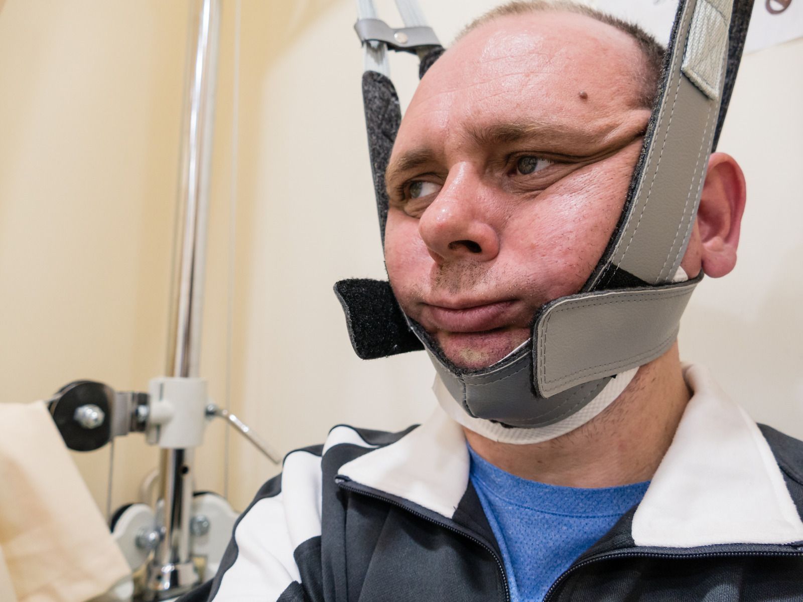 A man with a bandage on his face is sitting in a hospital bed.