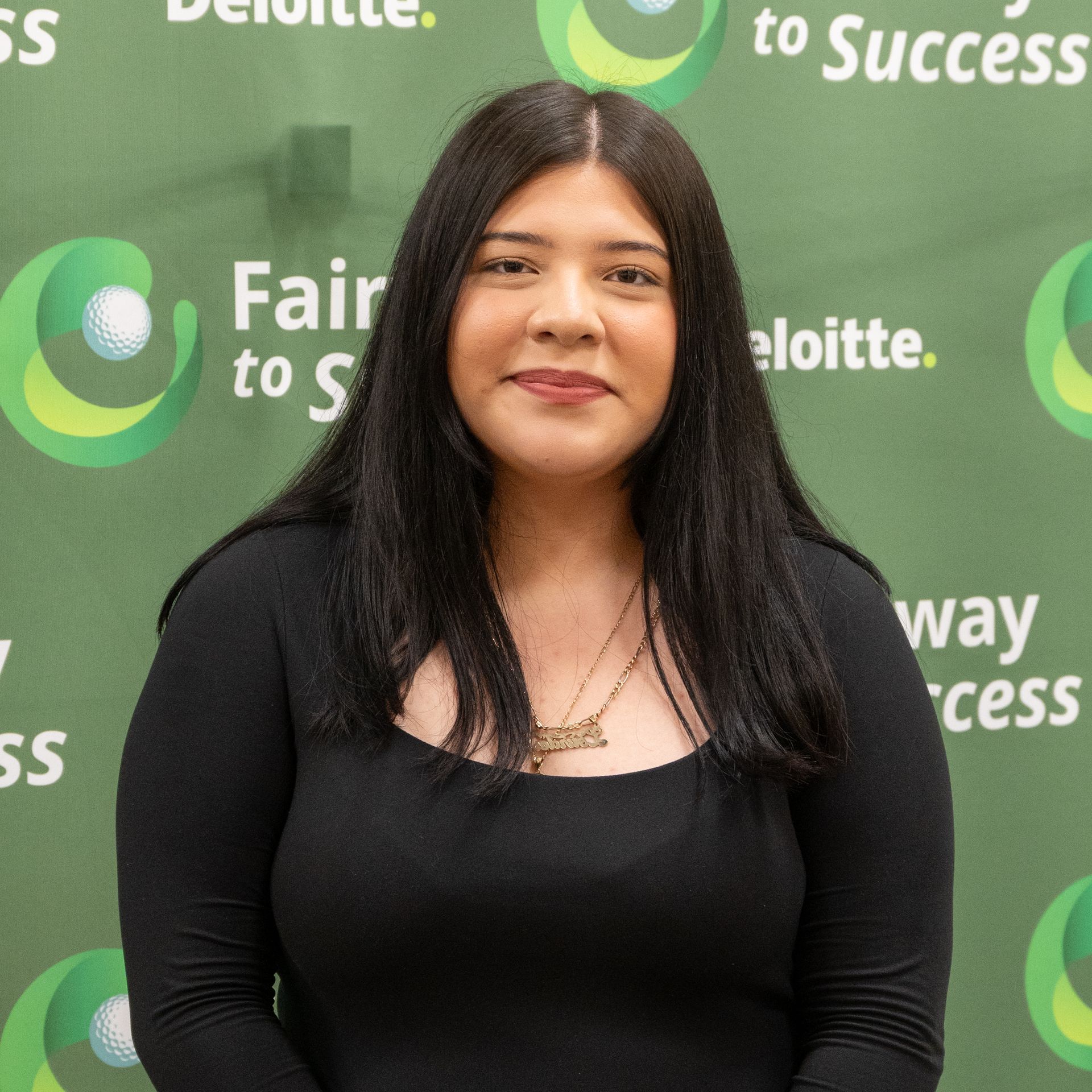 Woman in black top standing before a Deloitte “Fair to Success” backdrop.