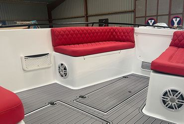 the inside of a boat with red cushions and speakers .