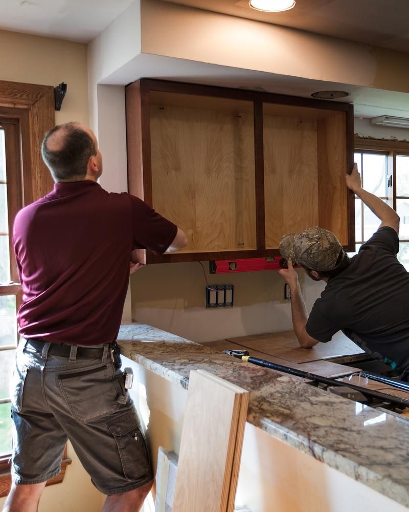 Two Men Are Measuring a Cabinet in A Kitchen — Smith's Joinery in Bangalow, NSW