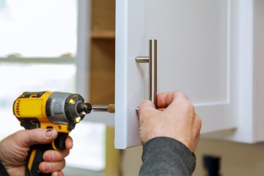 A Person Is Installing a Cabinet Handle with A Drill — Smith's Joinery in Yamba, NSW