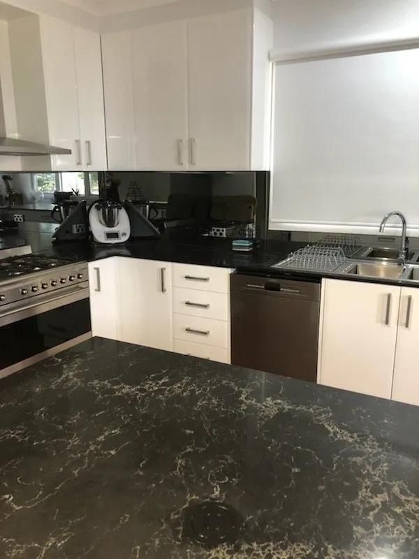 A Kitchen with Black Counter Tops, White Cabinets, a Stove and A Sink — Smith's Joinery in Casino NSW