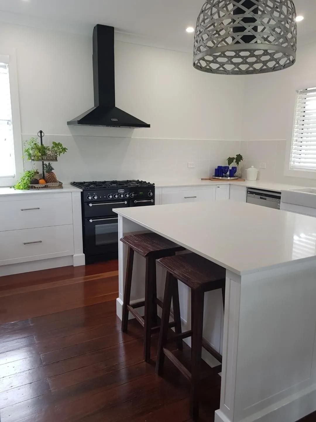 A Kitchen with White Cabinets, Stools, a Stove, and A Large Island — Smith's Joinery in Casino, NSW