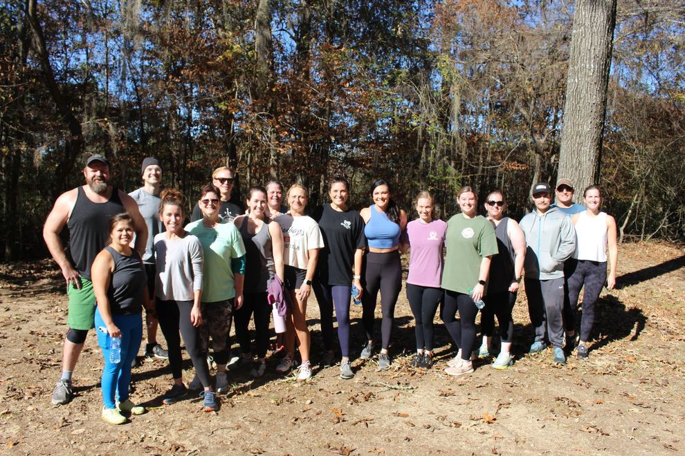 A group of people are posing for a picture in the woods.