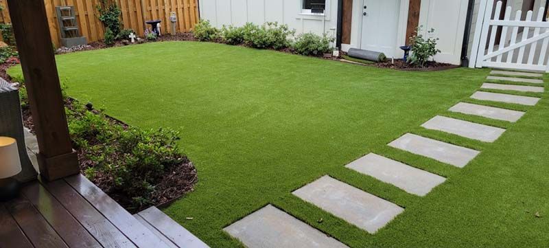 A backyard with a lush green lawn and a stone walkway.