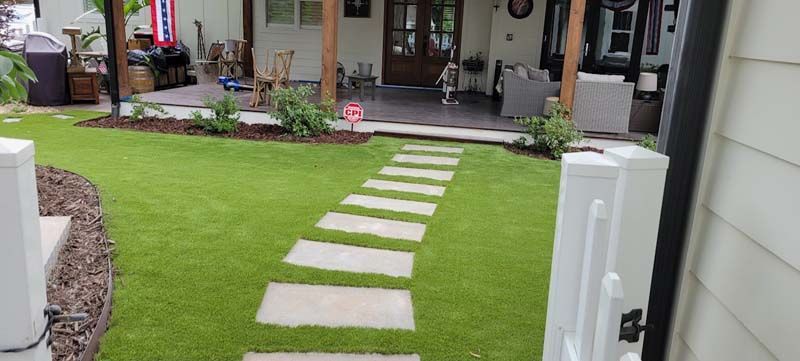 A house with a lush green lawn and a walkway leading to it.