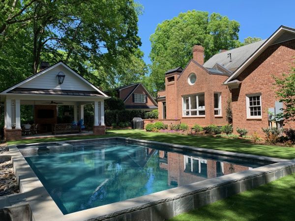 A large swimming pool in front of a large brick house