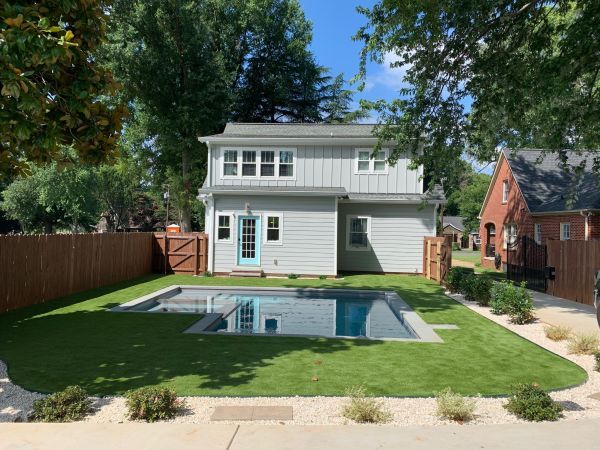 A white house with a large swimming pool in the backyard.
