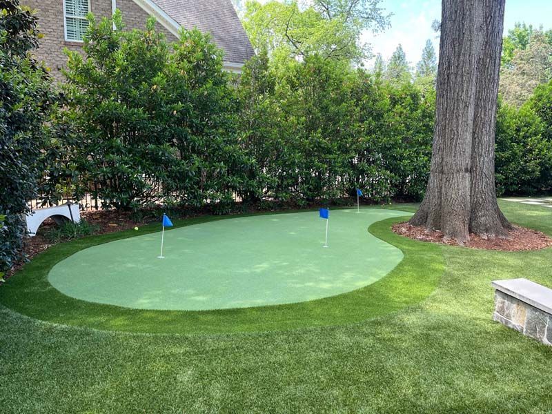 A green putting green in the backyard of a house.