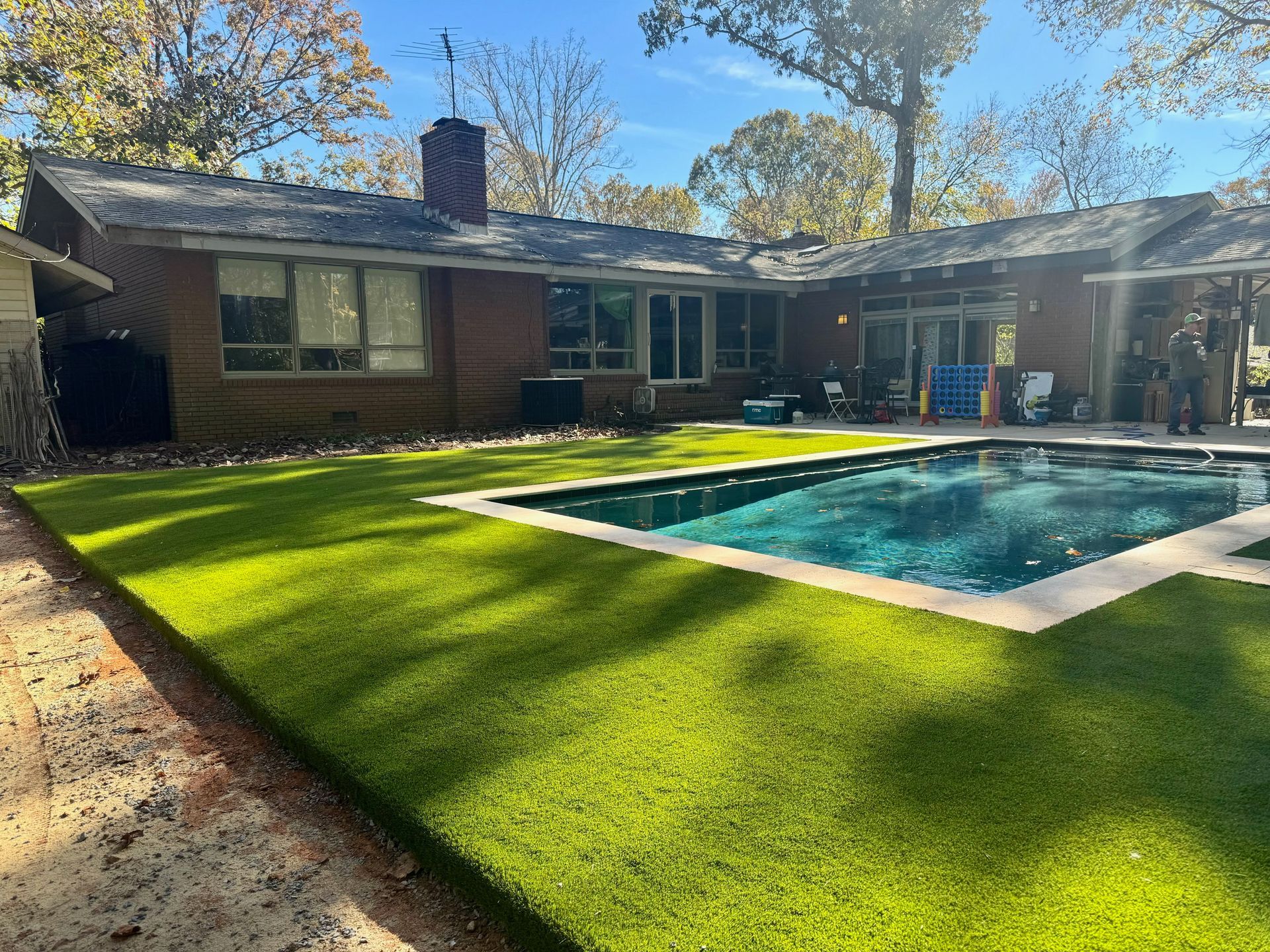 A large swimming pool is in the backyard of a house.