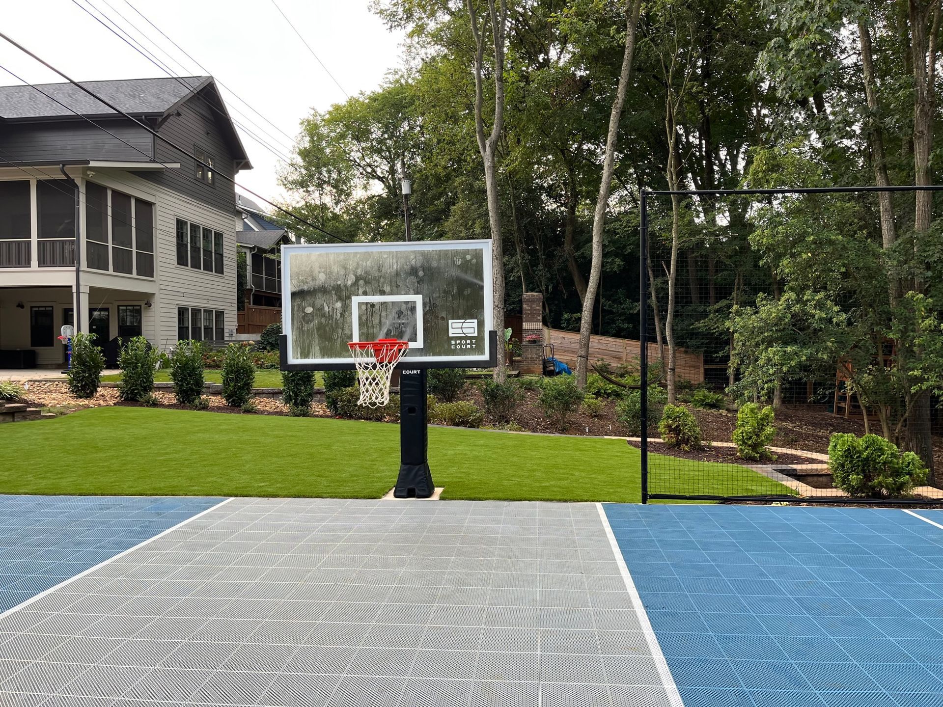 There is a basketball hoop in the backyard of a house.