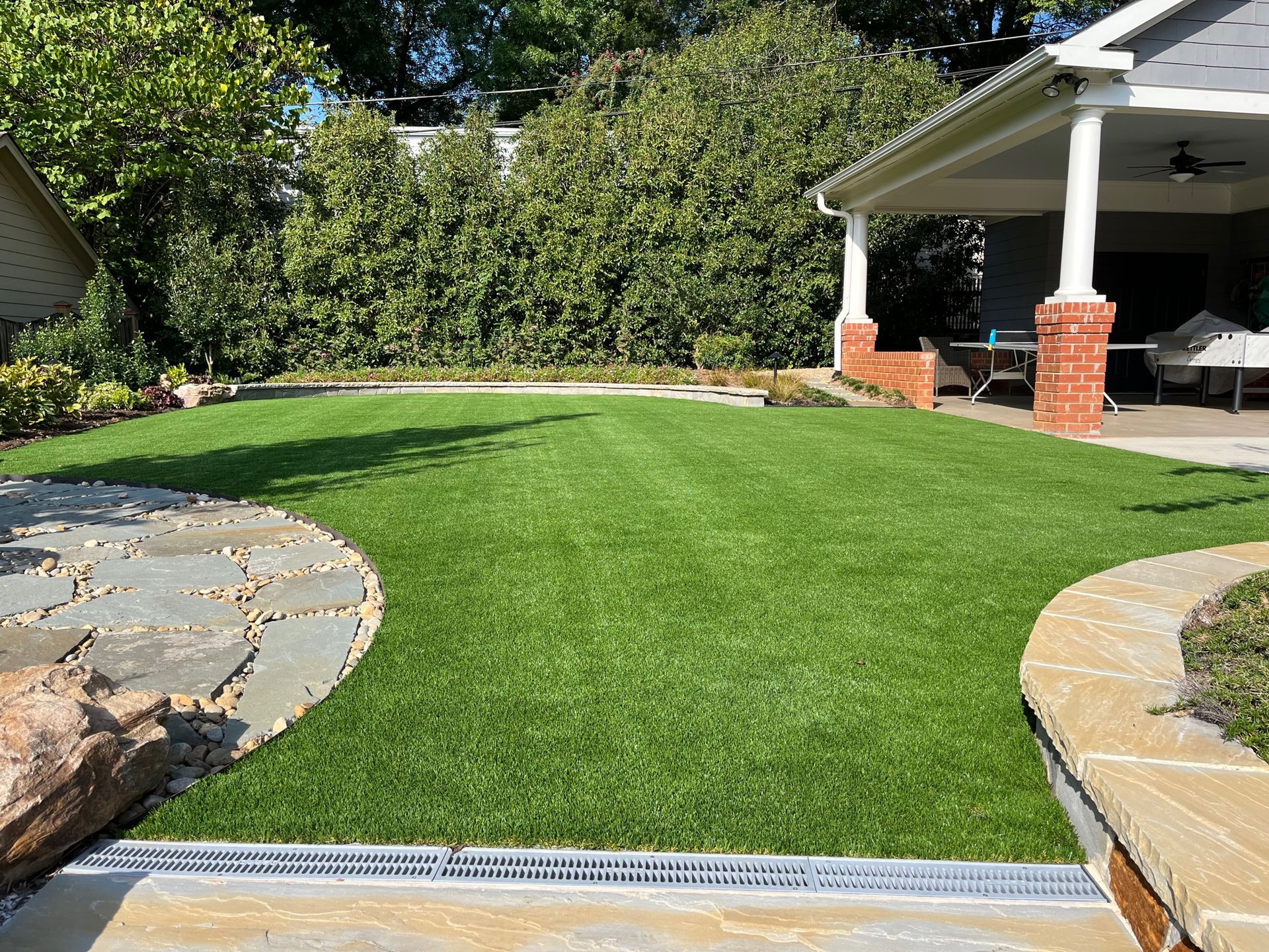 A lush green lawn in front of a house with a stone walkway.