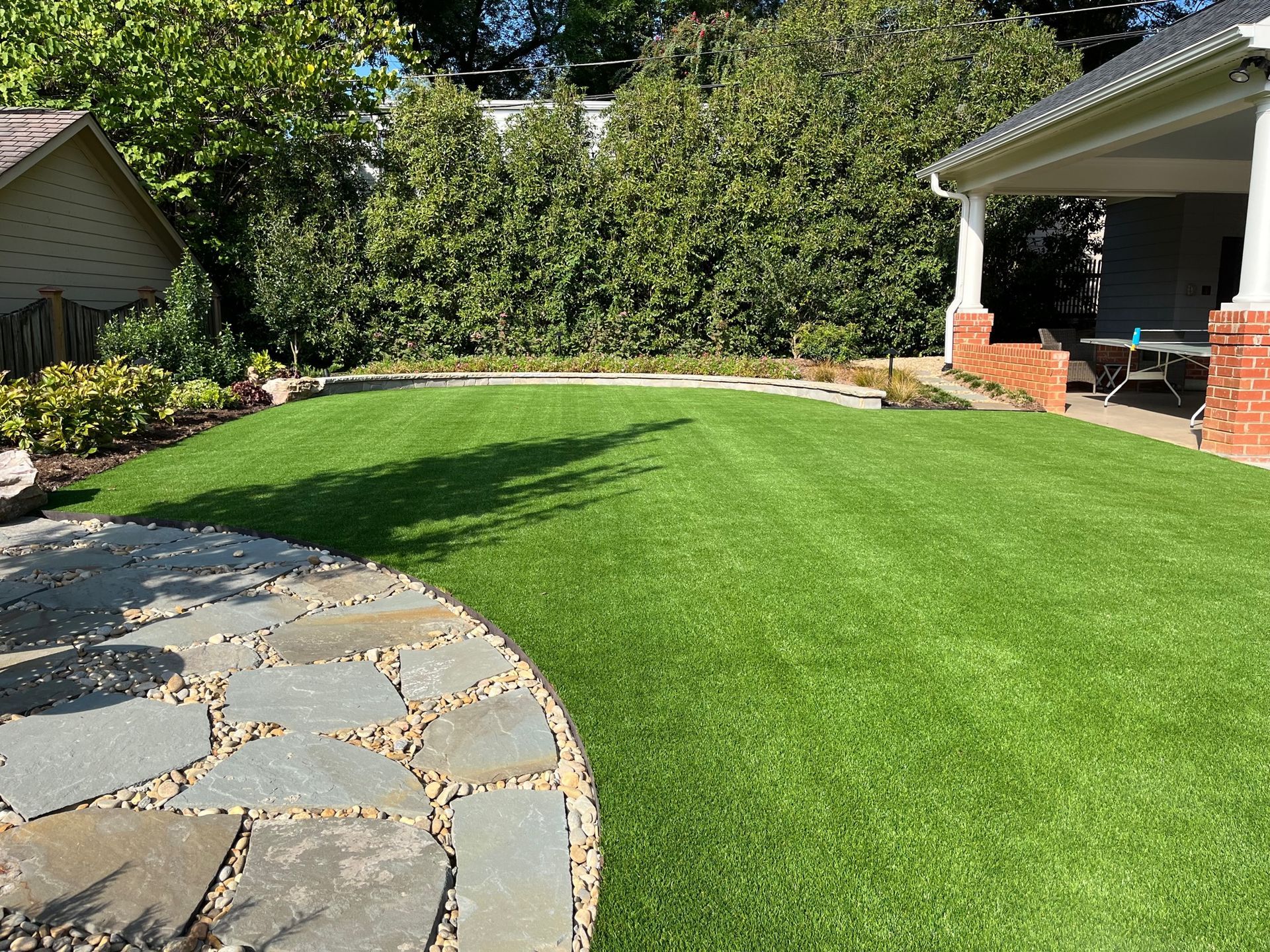 A lush green lawn with a stone walkway leading to a house.